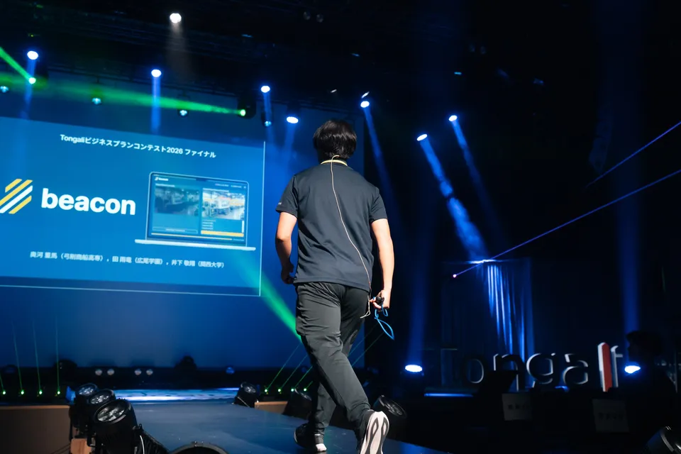 Rear view of Toma Okugawa walking toward the screen showing the beacon title slide at the Tongali Business Plan Contest 2026 Final