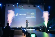 Wide shot of Toma Okugawa pitching Beacon on stage at the Tongali Business Plan Contest 2026 Final, with the presentation screen behind him